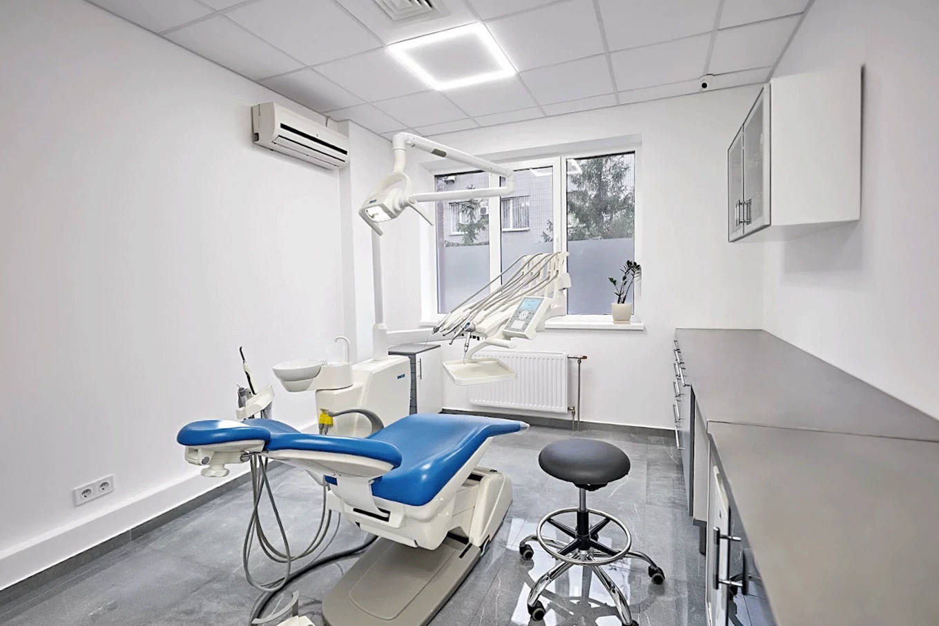 Світлий стоматологічний кабінет DRT Clinic із синім кріслом та сучасним обладнанням