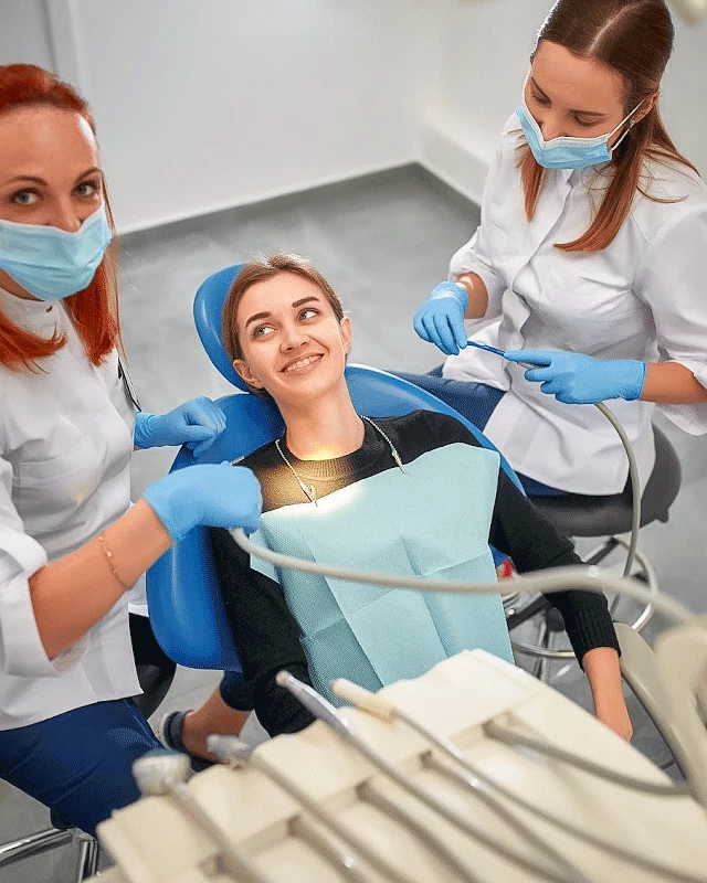 Пацієнтка у стоматологічному кріслі разом із двома лікарками DRT Clinic